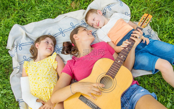妈和她两个孩子在公园弹吉他放松图片