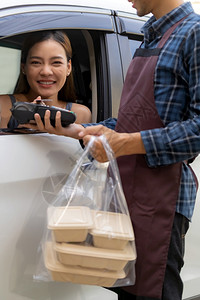 亚洲女客户在接送食品餐饮时将移动支付无接触技术作为流动支付无接触技术在科罗纳新冠virus新冠19大流行后驾车路程更受欢迎图片