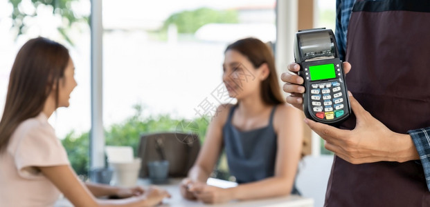 服务员手持信用卡阅读器与餐厅背景的客户进行无接触付款与客户进行无接触付款新的普通餐馆无接触付款概念图片