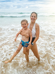 笑着母亲将儿子带出海水的肖像图片