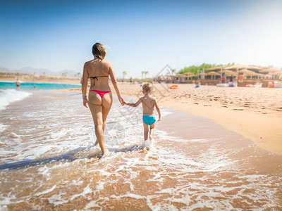 母亲和儿子在沙滩上行走图片