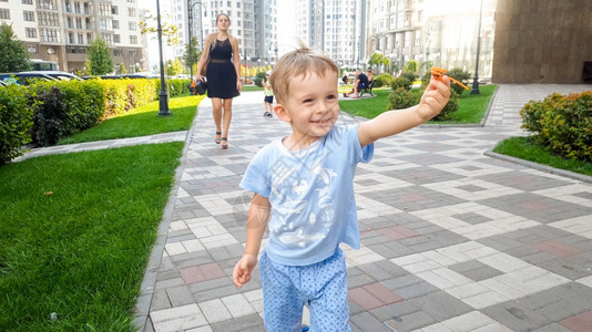 喜笑快乐的幼儿男孩在公园里跑动持有小型塑料玩具直升机孩子们有积极的情绪笑小孩幼儿有快乐笑幼儿男孩在公园里跑动持有小型玩具直升机图片