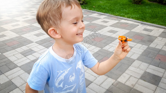 喜笑快乐的幼儿男孩在公园里跑动持有小型塑料玩具直升机孩子们有积极的情绪笑小孩幼儿有快乐笑幼儿男孩在公园里跑动持有小型玩具直升机图片