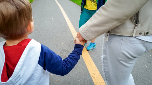 3岁的幼儿男孩手抱母亲在街上行走图片