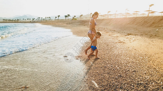 喜笑的3岁幼儿男孩在日落时沙滩上散步和放松的美丽照片家庭在夏季海滩度假期间有愉快的时光喜笑的3岁幼儿男孩在日落时沙滩上散步和放松图片