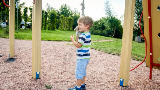 3岁的肖像在操场上玩耍试图爬公园的大绳子图片