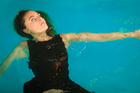 女人在游泳池水中做梦年轻女孩穿黑衣漂浮图片