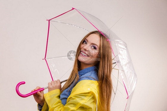 身着防水黄色大衣站在雨伞下玩得开心的雨中微笑女孩气象预报和天季节概念身着雨伞下防水大衣的妇女图片