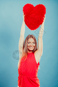 穿着红色心型枕头的漂亮可爱年轻女孩在工作室里微笑图片