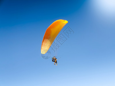 专业滑翔伞教练的美丽照片其中毛虫在降落伞上飞翔直蓝天专业滑伞教练的美丽图像直飞蓝天毛虫的滑翔伞教练美丽图像图片