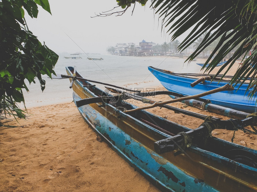 海滩上热带大雨的陶瓷照片沙滩上的旧木制渔船海滩上热带大雨的陶瓷图像沙滩上的旧木制渔船图片