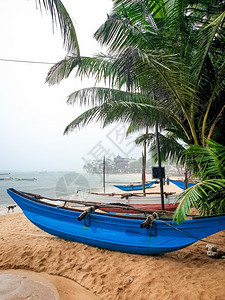 斯里兰卡雨中潮湿沙滩上的老传统渔船美丽照片图片