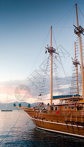 日落光照线下港务上美丽的木制历史船垂直照片图片