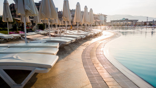 清晨在泳池边的空日光床照片没有人游泳池空夏季海滩旅馆度假胜地无人游泳池图片
