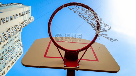 蓝天和城市居住区高楼对蓝天和使用网的篮球环近视照片图片