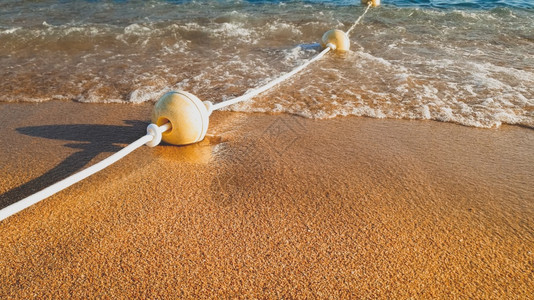 平静海浪滚动和在沙海岸浮标上摇动的近距离照片平静海浪滚动和在沙海岸浮标上摇动的近距离图像图片