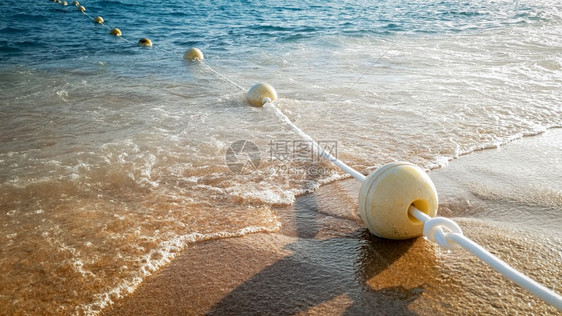 平静海浪滚动和在沙海岸浮标上摇动的近距离照片平静海浪滚动和在沙海岸浮标上摇动的近距离图像图片