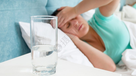 床垫上的水杯子用来对付床上偏头痛的患病妇女图片
