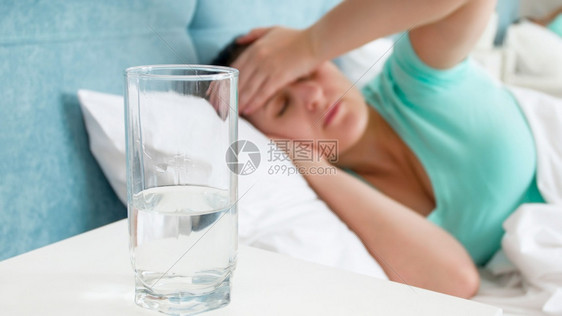 床垫上的水杯子用来对付床上偏头痛的患病妇女图片