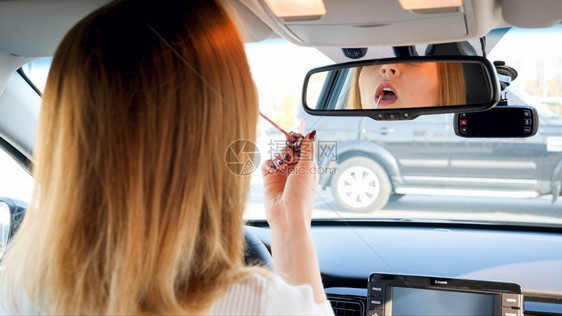 女人使用汽车镜子涂口红的肖像图片
