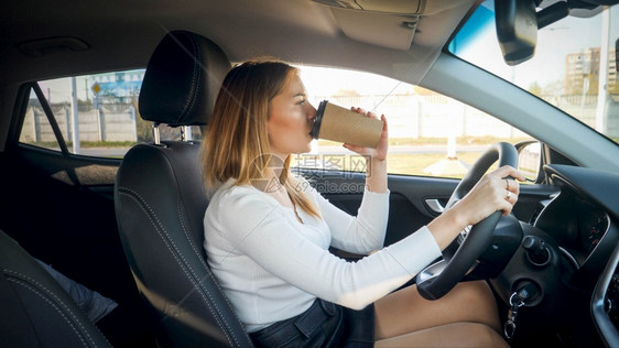 一边开车一边喝咖啡的女司机肖像图片