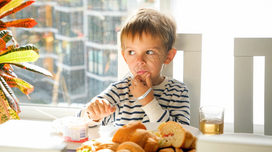 坐在饭桌后面吃早餐的小男孩坐在饭桌后面吃早餐的小男孩肖像图片
