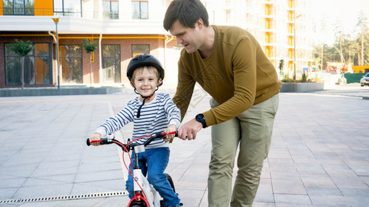 微笑的小男孩和年轻父亲一起骑着第辆自行车图片