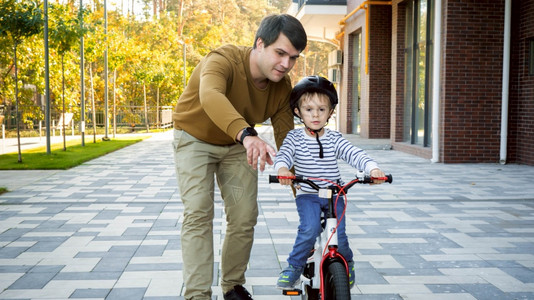 年轻有爱心的父亲教儿子骑自行车图片