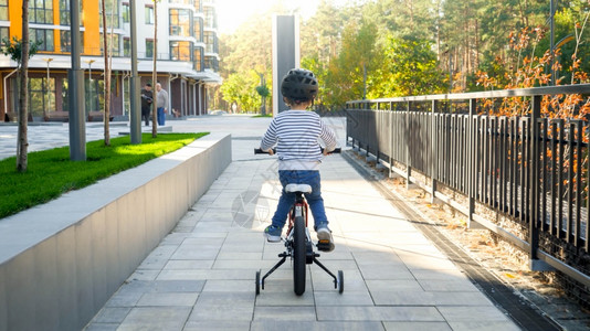 小男孩骑自行车第一次在路上小男孩骑自行车第一次在路上骑脚踏车的后视照片图片