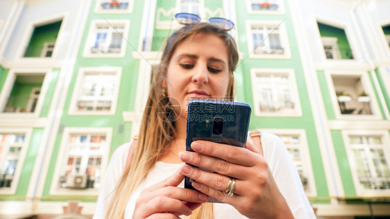 年轻女将智能手机握在城市街道上图片
