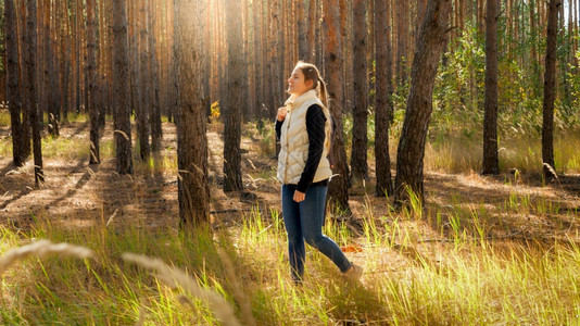 美丽的年轻女子在温暖的阳光天气享受在森林中行走图片