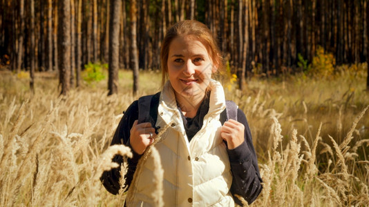 在温暖的秋天带着背包在森林中徒步的美丽微笑女孩肖像图片