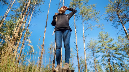 年轻女徒步旅行者用手保护她的眼睛免受阳光照射远看年轻女徒步旅行者用手保护她的眼睛免受阳光照射远看图片