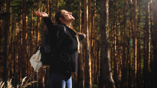 年轻女在森林中穿梭双手伸展享受温暖的太阳光自由与然和谐的概念年轻女在森林中穿梭享受温暖的太阳光自由与然和谐的概念图片