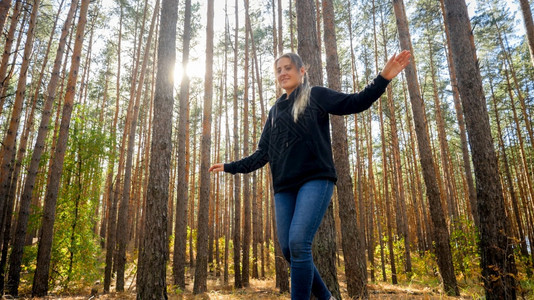 美丽的女旅游者在森林木上平衡的肖像图片