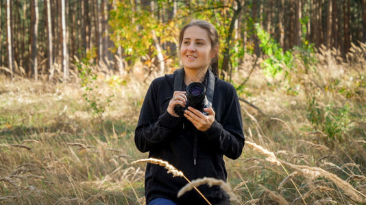 Beautfiul年轻女子的肖像与数字相机在野林中行走图片
