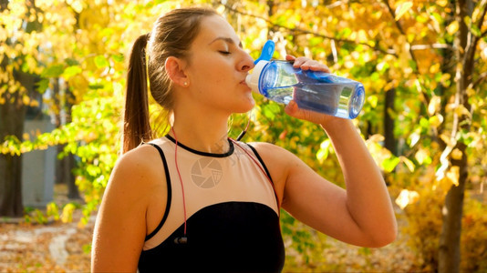 秋季公园体育训练期间美丽的年轻女子饮用水的肖像秋季公园体育训练期间美丽的年轻女子饮用水的肖像图片