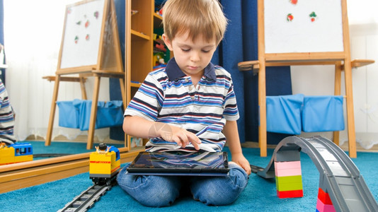 小男孩坐在地板上玩平板电脑图片