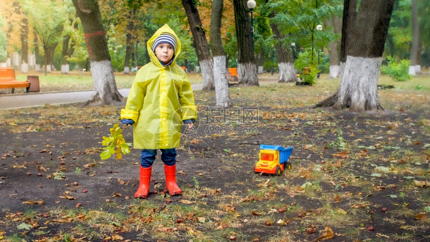雨天在公园穿雨衣玩耍的男孩