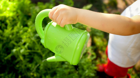 小男孩在花园里拿着免费塑料水壶图片