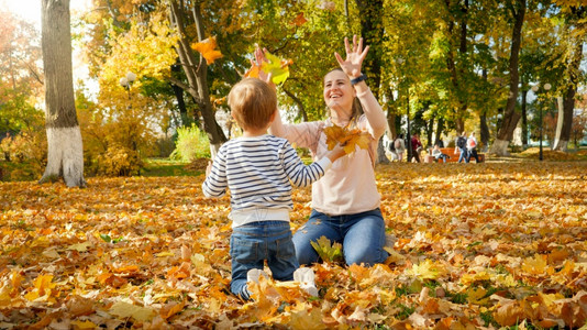 妈和儿子在公园扔秋叶图片
