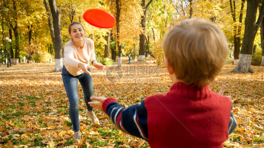 小男孩和他的妈妈在公园里玩飞盘图片