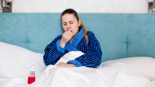 躺在床上和咳嗽的年轻患病妇女肖像图片素材