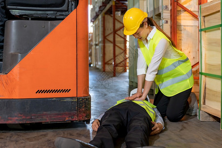 在仓库经理叉车事故后躺仓库地板上之后亚洲工人做了心肺复苏使用安全第一概念和商业保险图片