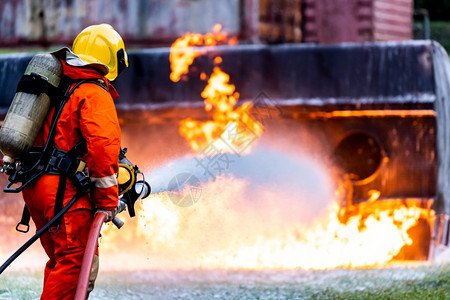 消防员使用化学泡沫灭火器与油轮卡车事故的火灾作斗争消防员安全事故和公共服务概念图片
