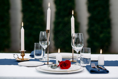 餐桌布置葡萄酒杯蜡烛和鲜花在板上没有人豪华银器白桌布户外餐具布蜡烛和花图片