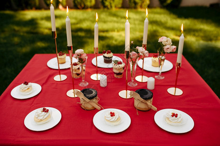 餐桌布局有甜和蜂蜜的茶会没有人豪华银器在红桌布上餐室在户外夏季草地的婚礼庆祝活动餐桌布局有甜和蜂蜜的茶会图片
