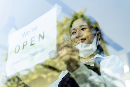 亚洲女服务员为新的普通餐厅设置开放标志和社交距离新的正常餐厅生活方式概念图片