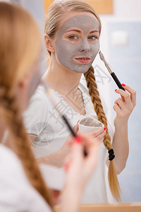 面部干燥皮肤和身体护理家庭内容光化处理概念快乐的年轻女用刷子在脸上戴灰色的泥面罩快乐的年轻女用泥面罩在脸上图片
