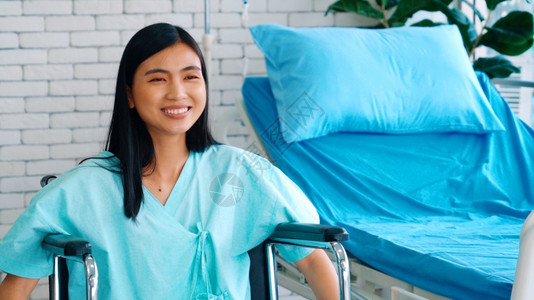 在医院病房轮椅上坐在的亚洲年轻快乐妇女医疗保健和病人治概念图片